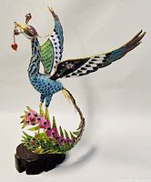 Front diagonal view of Chinese cloisonné phoenix sculpture showing detailed wing and body enamel work in blue, green, and pink.