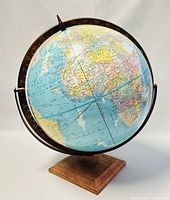 Angled front view of the globe showing Africa, Europe, and the surrounding Atlantic Ocean, mounted on a wood base with metal/plastic meridian frame.