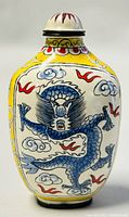 Front view of the vintage Chinese enamel hand painted perfume bottle featuring a dynamic blue dragon with clouds on a yellow background.