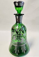 Front and angled views of the vintage green glass decanter with detailed silver overlay and matching lidded stopper.