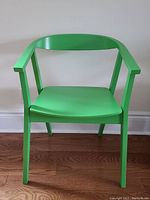 Front view of green IKEA Stockholm chair showing curved backrest and armrests, solid wood legs and smooth seat.