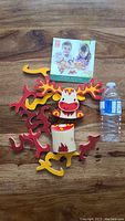 Full set of 12 colorful wooden balancing pieces arranged with instruction box and water bottle for scale