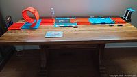 Full view of Hot Wheels Track Builder System laid out on table showing loop, straight track sections, and cars placed on the track. Instruction booklet visible.