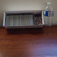 White storage box filled with over 400 Pokémon cards next to a water bottle for scale.