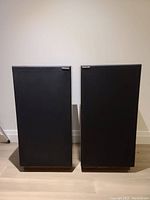 Front view of two StudioLab black cloth covered speakers side by side on floor