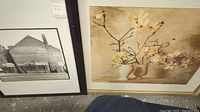 Photo showing the black and white photograph and the floral print framed art pieces leaning against a wall.