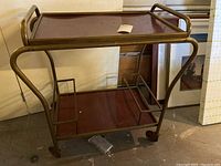 Side view of the two-tiered rolling cart showing the metal frame and plastic shelves on caster wheels.