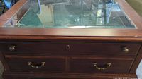 Top of the coffee table showing glass top and wooden drawers with metal handles beneath.