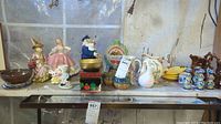 Wide view of the shelf showing all ceramic and figurine items including copper lusterware pitchers, candleholders, snack dishes, figurines, and decorative boxes.