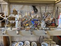 Four metal Christmas stocking hangers with holly leaf designs, one hanger bent down.