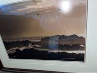 Photo showing the framed photograph featuring a rocky ocean shoreline at night, cloudy sky, and birds flying.