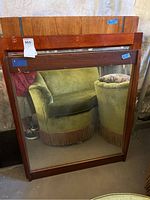 Full view photo of one large mirror with dark wood frame showing condition and reflections