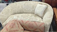 Full view of the sofa showing the floral cut velvet upholstery, crescent back style, and complementary down-filled pillow.