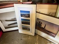 Four framed photos grouped together including black-and-white boat photo, white frame collage, lighthouse photo, and photo of large building.