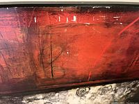 Close-up photo showing red-orange section of the abstract art with scratches and paint loss
