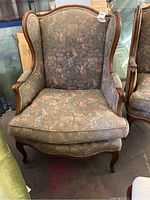 Front view of a wing back chair with floral upholstery and solid wood frame, showing overall condition.