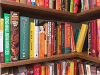 Photo showing an assortment of hard cover books on a wooden shelf, mostly nonfiction and literary titles.