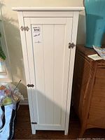 Front view of the white wooden cabinet with closed door and latch lock.