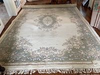Top-down view of entire rectangular area rug on hardwood floor showing central medallion and floral border