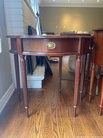 Front view showing demilune top and center drawer with brass pull