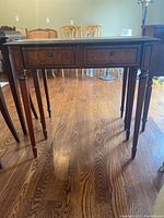 Full view of wooden console table showing front and legs on hardwood floor