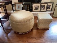 Both ottomans side by side on hardwood floor, showing size difference, fabric patterns, and tassel trims.