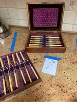 Full view of the set inside the original wooden box with purple lined interior showing multiple forks and utensils organized in slots.