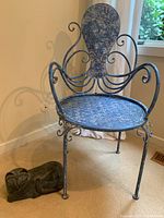 Full view of blue metal octopus chair with curled tentacle armrests and blue wooden cat doorstop placed beside it on carpet