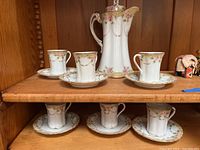 White porcelain Nippon hot chocolate pot with six cups and saucers on wooden shelf