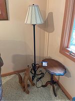 Black metal floor lamp, howling coyote figurine, and oak side table positioned in a carpeted corner near a window.