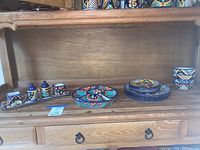 View of entire set including stacked plates, bowls, segmented platter and tray with small containers on wooden shelf.
