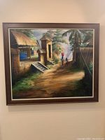Full front view of framed painting showing the village scene with woman carrying basket on her head.
