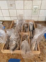 Wooden drawer organizer holding wrapped flatware pieces