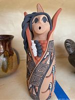 Close-up of Southwest storyteller figure showing painted geometric patterns, dark blue braided hair, and facial details