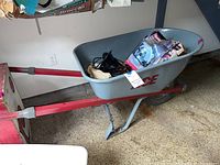 Gray ACE brand wheelbarrow with red frame and handles, containing various items