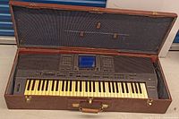 Full view of the Technics keyboard inside the open brown hard case showing the keys, control panel, and case interior.