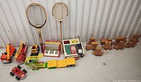 Wide shot of entire lot showing wooden train set, toy vehicles, tennis rackets, and toy musical instruments.