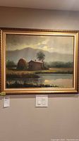 Framed landscape artwork hung on wall with visible label and light switches beneath it.