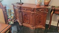 Front view of the solid wood buffet showing detailed carving on drawers and doors with warm reddish finish.