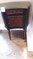 Front view of the wood cabinet showing drawer, door with inlay design, and legs