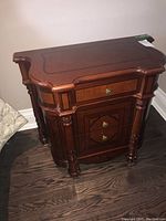 Front and side view of one bedside table showing overall shape, finish and hardware