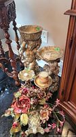 View of three cherub statues with bowls, faux floral basket, and decorative candle, showing arrangement and condition.