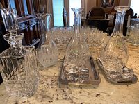 Showing all decanters on a countertop with shot glasses in the background - highlights variety and trays
