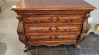 Front view of dresser showing three drawers and carved details