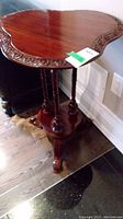 Side view showing scalloped wooden table top with carved floral edge and polished finish.
