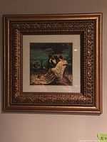 Framed print showing two women seated outdoors in a relaxed outdoor setting, ornate gold frame