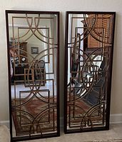 Pair of rectangular accent mirrors with geometric decorative metal overlay, framed in dark material, in a home setting