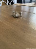Single view of wedding set ring showing silver-tone central ring with stones.