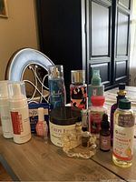 Photo showing all items included in the lot arranged on a table, mainly beauty and skincare products including sunless tanning, perfume, body sprays, and lotions.