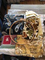 Photo of mixed fabric pieces and one wooden embroidery hoop on a wooden surface.